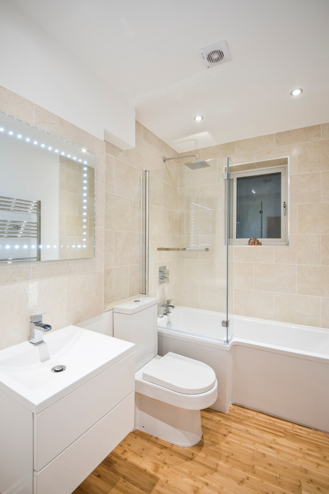 Ispirazione per una stanza da bagno design con ante lisce, ante bianche, vasca ad alcova, vasca/doccia, WC a due pezzi, piastrelle beige e pareti beige