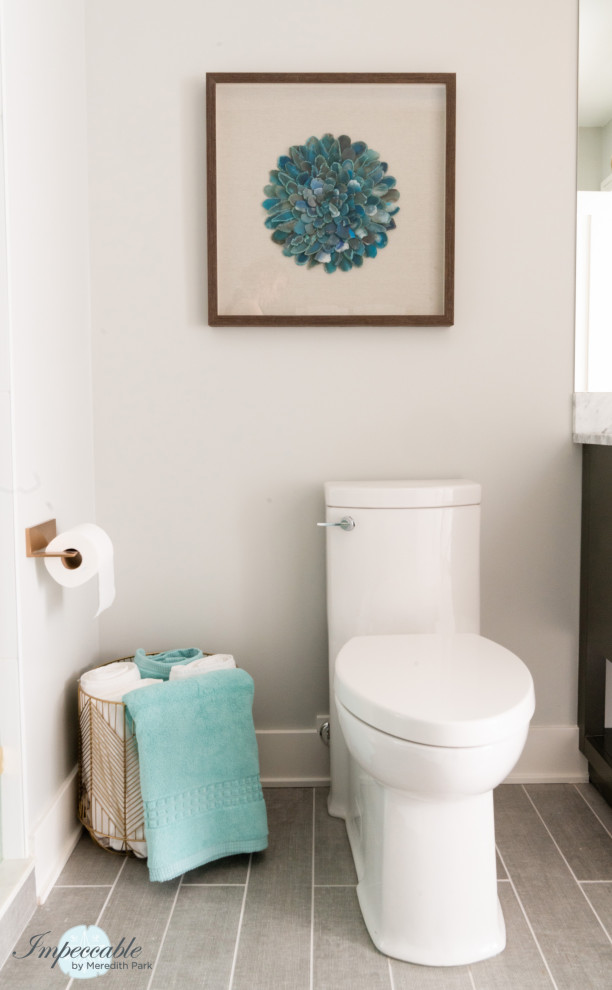 Exemple d'un WC et toilettes tendance de taille moyenne avec un placard à porte plane, des portes de placard grises, WC à poser, un carrelage bleu, des carreaux de porcelaine, un mur gris, un sol en carrelage de porcelaine, un lavabo encastré, un plan de toilette en marbre, un sol gris et un plan de toilette blanc.