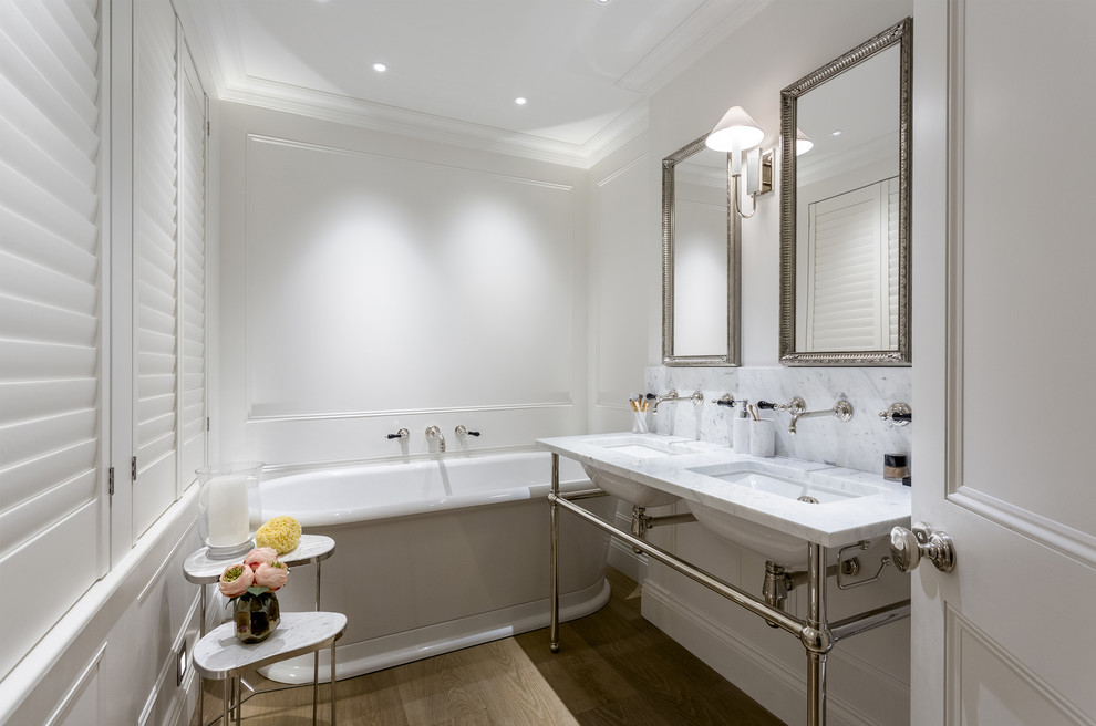 Mittelgroßes Modernes Duschbad mit weißen Schränken, freistehender Badewanne, weißer Wandfarbe, braunem Holzboden, Unterbauwaschbecken und Marmor-Waschbecken/Waschtisch in London
