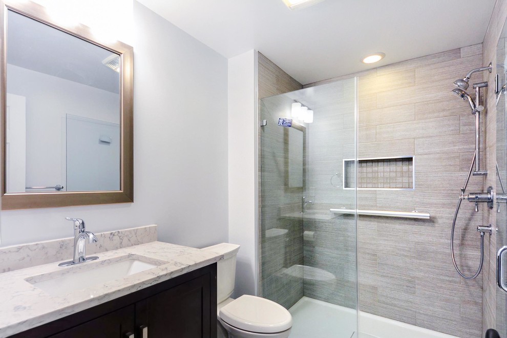 Photo of a medium sized classic grey and white ensuite bathroom in DC Metro with grey walls, an alcove shower, a two-piece toilet, beige tiles, a submerged sink, engineered stone worktops, brown floors, a single sink, a freestanding vanity unit, flat-panel cabinets, medium wood cabinets, porcelain tiles, ceramic flooring, a hinged door, white worktops and a wall niche.
