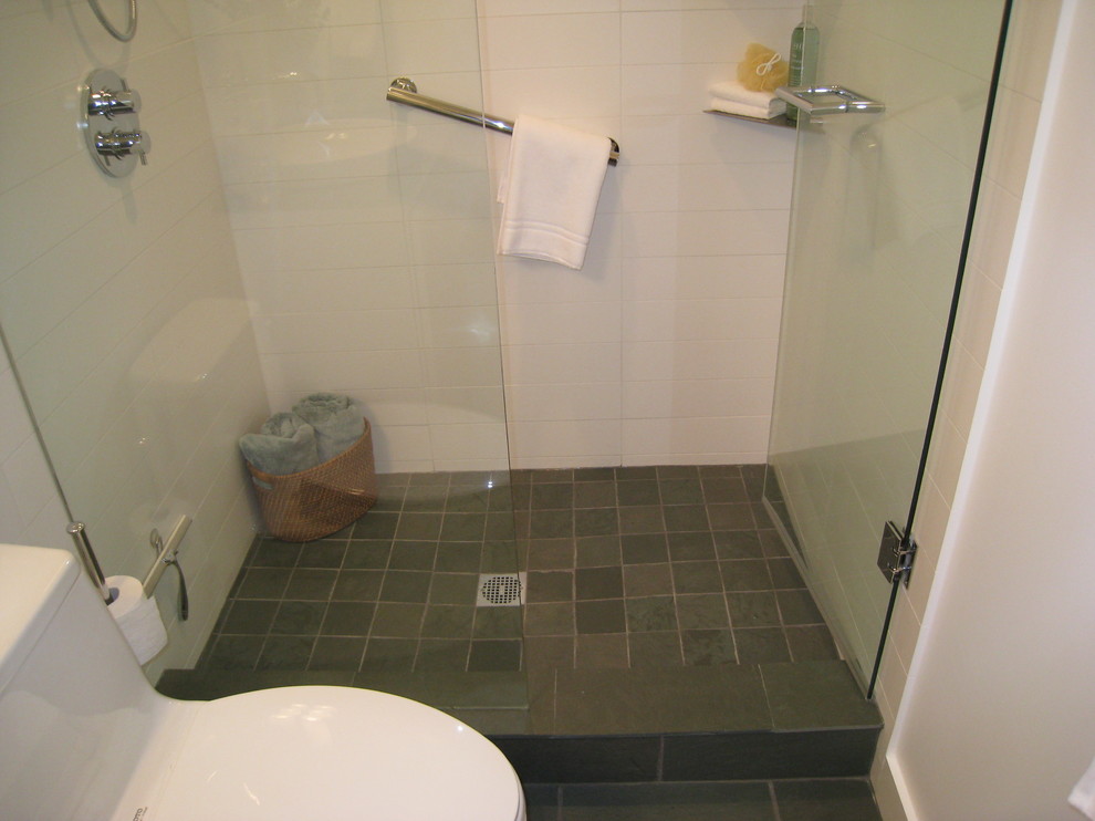 Immagine di una piccola stanza da bagno con doccia minimalista con ante lisce, ante bianche, top in vetro, doccia alcova, WC monopezzo, piastrelle bianche, piastrelle in gres porcellanato, pareti bianche e pavimento in ardesia