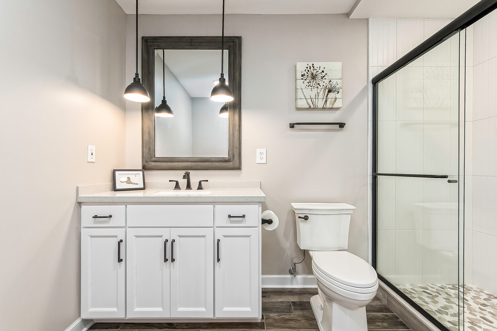 Пример оригинального дизайна: ванная комната среднего размера в стиле неоклассика (современная классика) с фасадами с утопленной филенкой, белыми фасадами, душем в нише, раздельным унитазом, белой плиткой, керамогранитной плиткой, бежевыми стенами, полом из керамогранита, душевой кабиной, врезной раковиной, коричневым полом, душем с раздвижными дверями, столешницей из искусственного кварца и белой столешницей