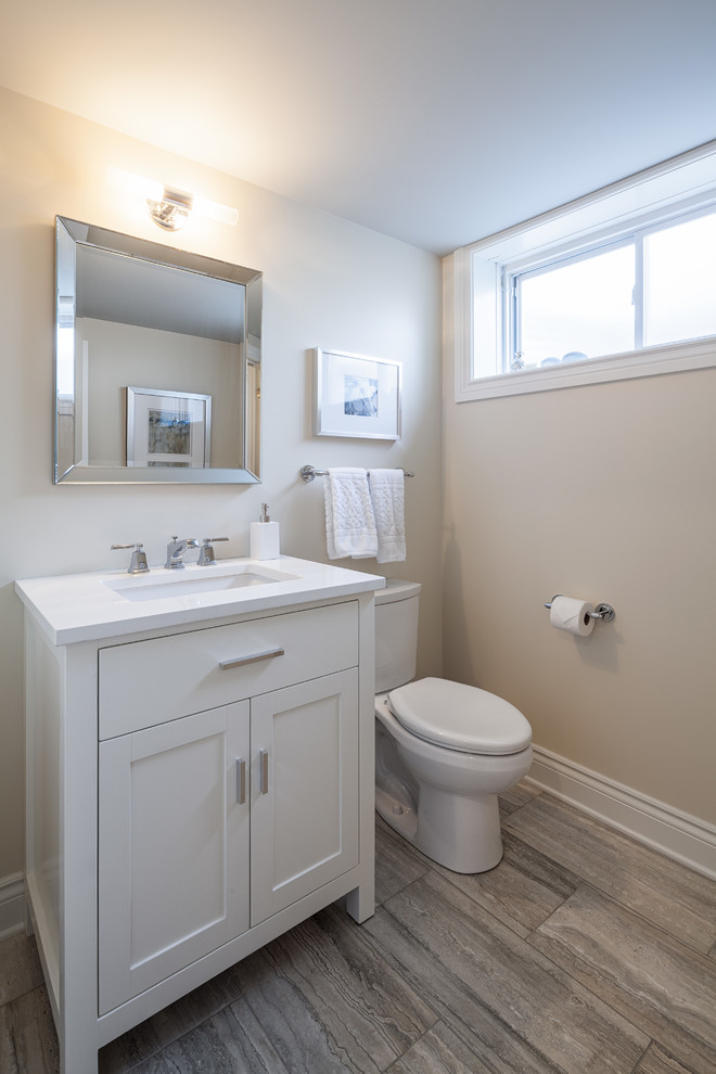 Cette image montre une petite salle de bain traditionnelle avec un placard à porte shaker, des portes de placard blanches, WC séparés, un carrelage de pierre, un mur beige, un sol en marbre, un lavabo encastré, un plan de toilette en quartz modifié et un carrelage beige.