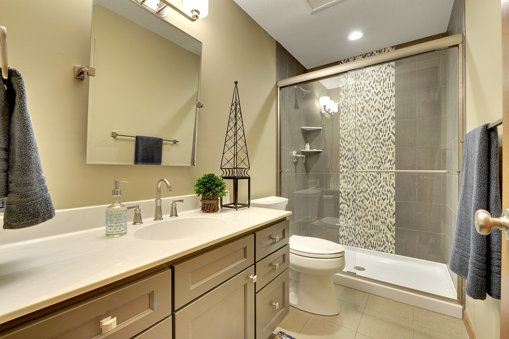 Пример оригинального дизайна: маленькая ванная комната в стиле неоклассика (современная классика) с серыми фасадами, душем в нише, серой плиткой, керамогранитной плиткой, бежевыми стенами, полом из керамической плитки, столешницей из искусственного камня, раздельным унитазом, монолитной раковиной, фасадами с утопленной филенкой, душем с раздвижными дверями, душевой кабиной и бежевым полом для на участке и в саду