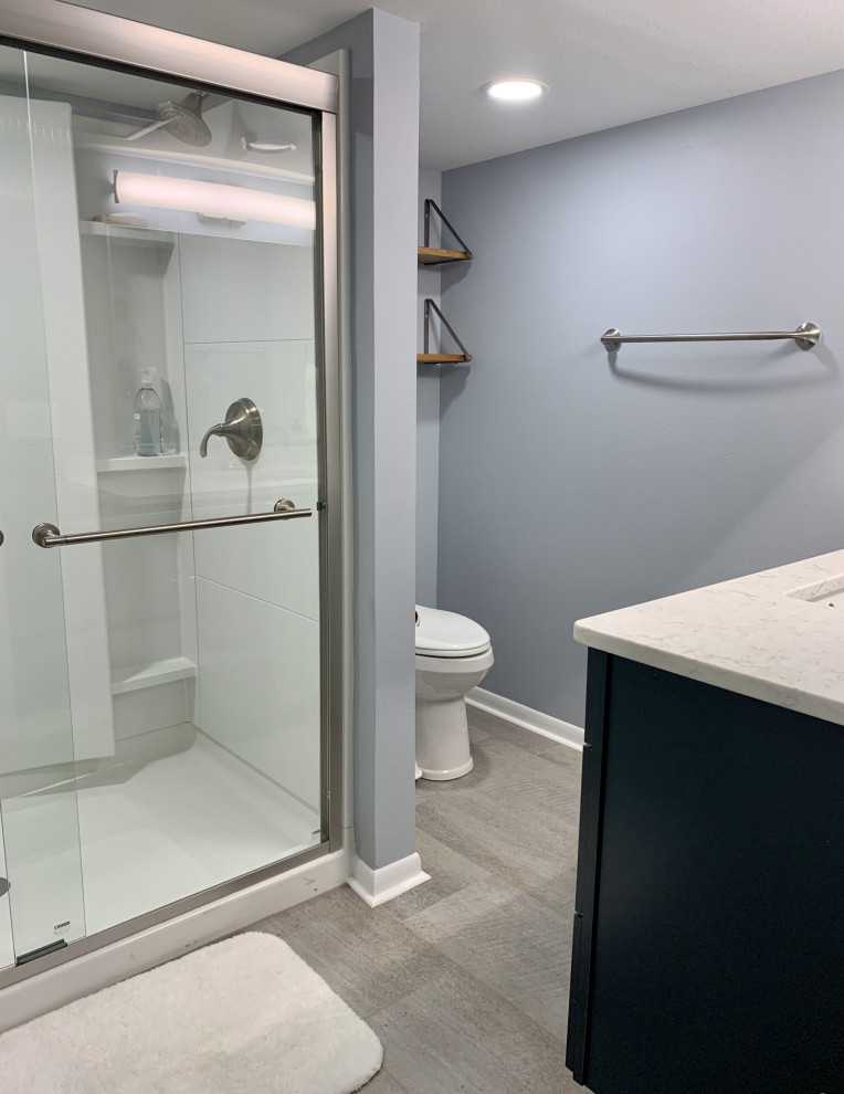 Inspiration for a medium sized modern shower room bathroom in Other with shaker cabinets, blue cabinets, an alcove shower, a two-piece toilet, blue walls, vinyl flooring, a submerged sink, engineered stone worktops, grey floors, a sliding door, white worktops, a single sink and a freestanding vanity unit.