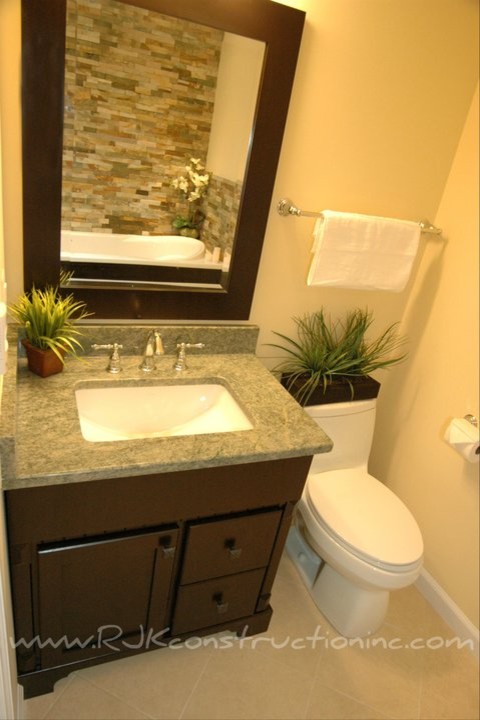 Cette photo montre une salle de bain tendance en bois foncé avec un lavabo encastré, un placard à porte shaker, un plan de toilette en granite, une baignoire posée, WC à poser, un carrelage gris, des dalles de pierre, un mur beige et un sol en carrelage de céramique.