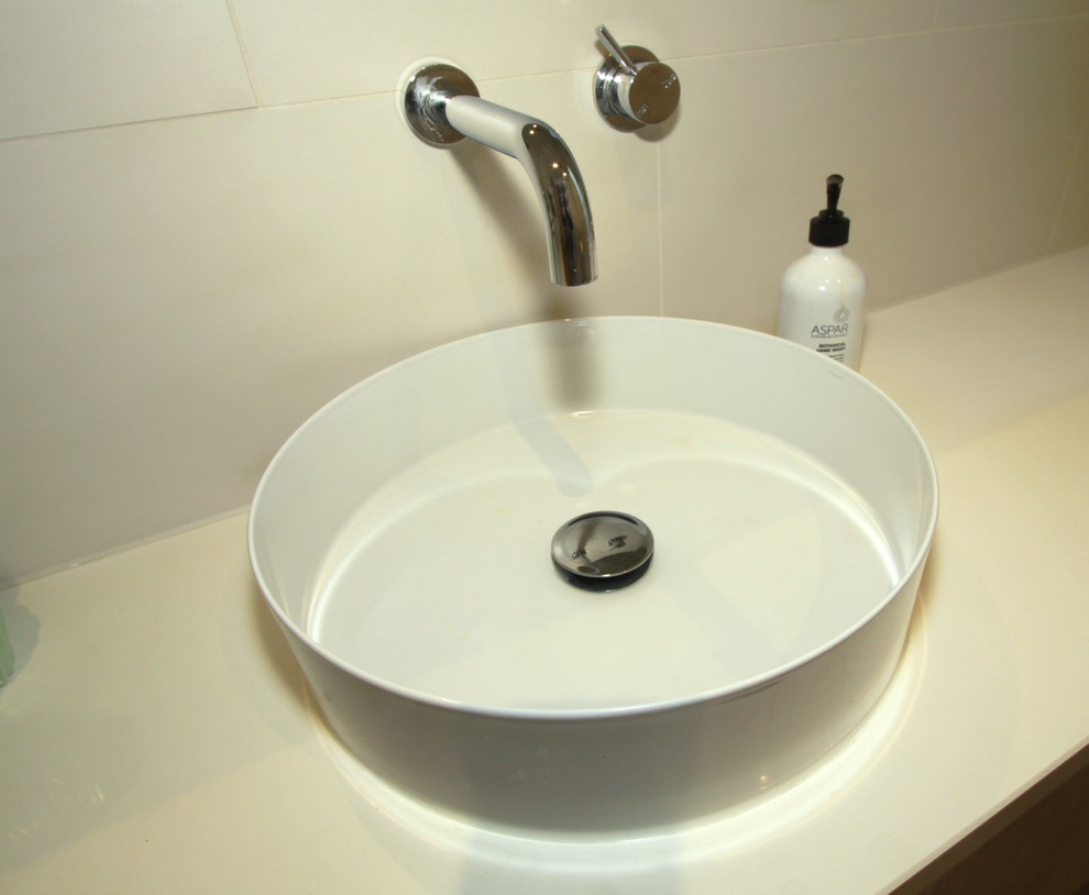 Modernes Badezimmer mit flächenbündigen Schrankfronten, weißen Schränken, weißen Fliesen, weißer Wandfarbe, Aufsatzwaschbecken und Mineralwerkstoff-Waschtisch in Melbourne
