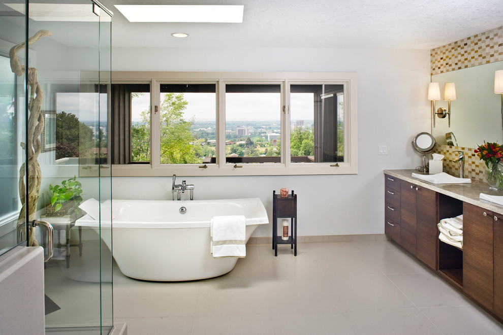 Exemple d'une grande salle de bain principale tendance en bois foncé avec une baignoire indépendante, un lavabo posé, un placard à porte plane, un plan de toilette en calcaire, une douche d'angle, un carrelage multicolore, un carrelage en pâte de verre, un mur gris et un sol en carrelage de céramique.