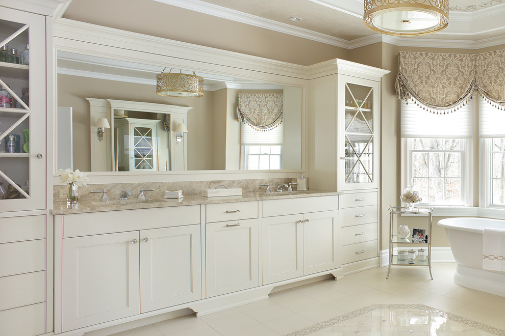 Exempel på ett stort klassiskt en-suite badrum, med luckor med infälld panel, vita skåp, ett fristående badkar, beige väggar, kalkstensgolv, ett undermonterad handfat, granitbänkskiva och vitt golv