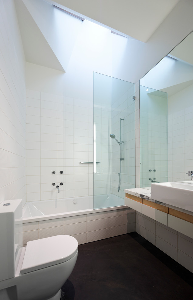 メルボルンにある高級な小さなコンテンポラリースタイルのおしゃれな浴室 (大理石の洗面台、ベッセル式洗面器、フラットパネル扉のキャビネット、ドロップイン型浴槽、シャワー付き浴槽	、一体型トイレ	、白いタイル、磁器タイル、白い壁、コンクリートの床) の写真