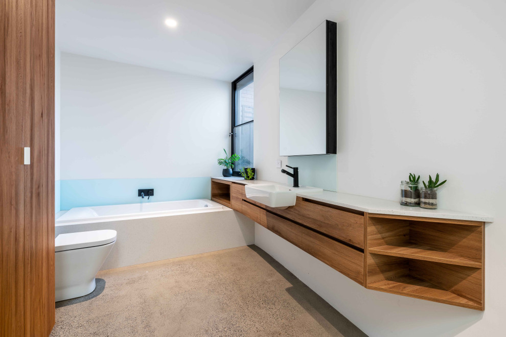 Foto de cuarto de baño principal, único y flotante contemporáneo con puertas de armario de madera oscura, bañera encastrada, paredes blancas, suelo de cemento, lavabo suspendido, encimera de madera y suelo gris