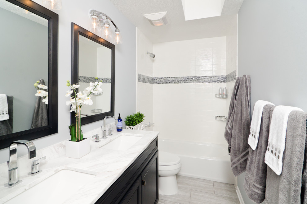 This is an example of a medium sized traditional family bathroom in Chicago with raised-panel cabinets, dark wood cabinets, an alcove bath, an alcove shower, a two-piece toilet, white tiles, porcelain tiles, grey walls, porcelain flooring, a submerged sink and marble worktops.
