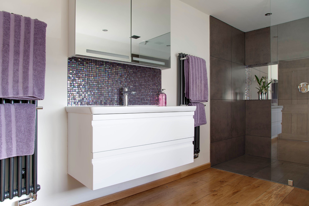 This is an example of a large contemporary grey and purple bathroom in Other with flat-panel cabinets, white cabinets, an alcove shower, multi-coloured tiles, mosaic tiles, white walls and medium hardwood flooring.