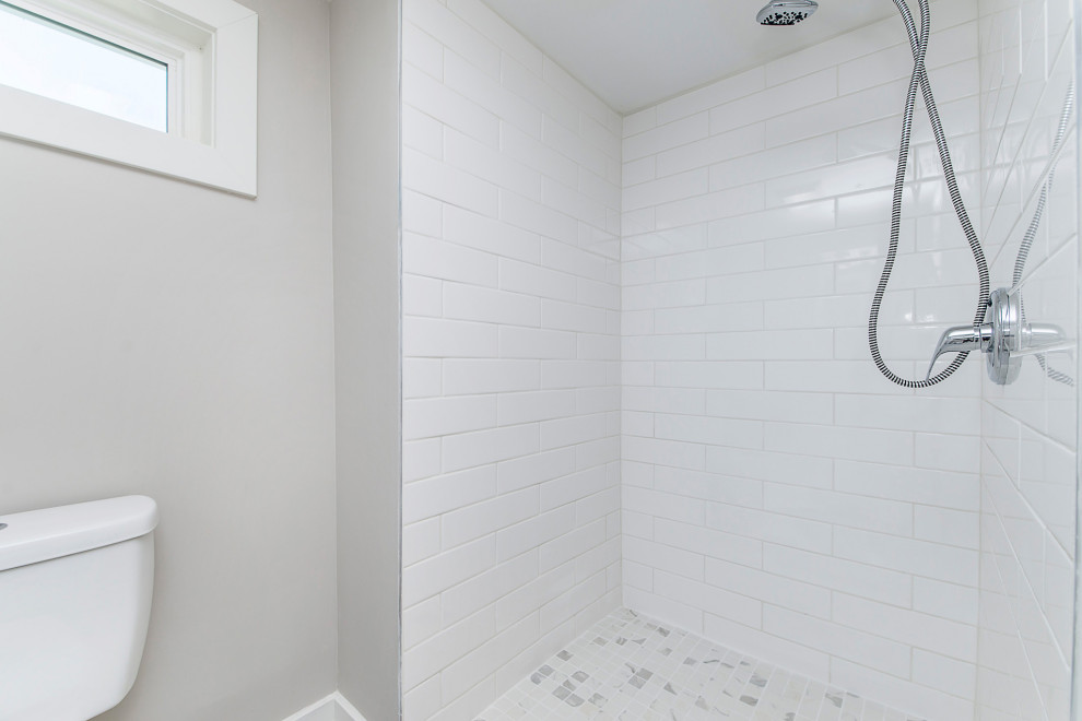 Bild på ett litet funkis grå grått badrum, med möbel-liknande, vita skåp, en öppen dusch, en toalettstol med separat cisternkåpa, röd kakel, tunnelbanekakel, grå väggar, klinkergolv i keramik, bänkskiva i kvartsit och med dusch som är öppen