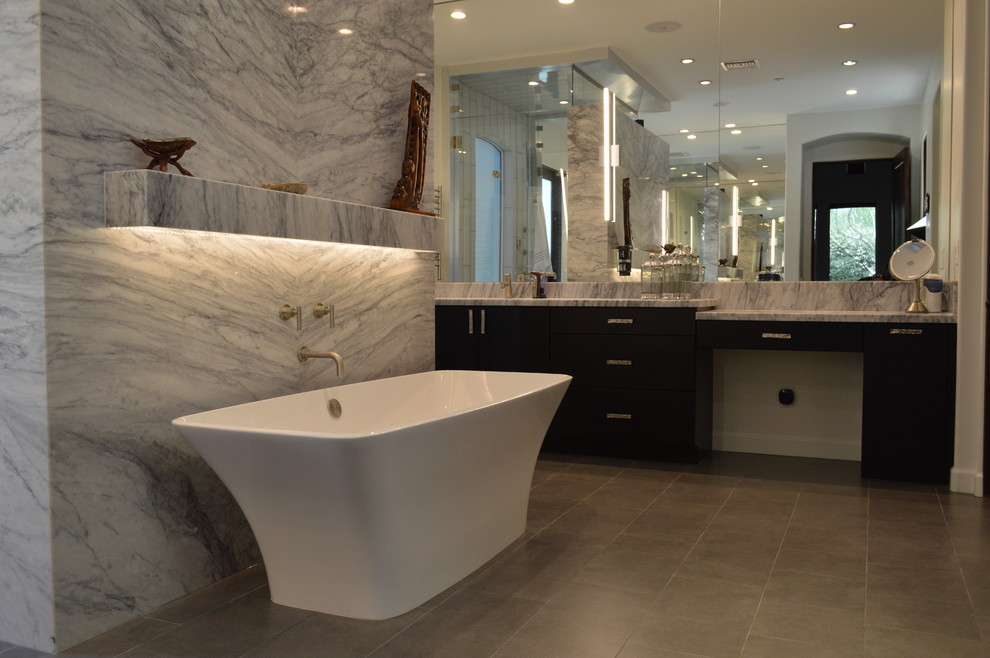 Bild på ett stort funkis en-suite badrum, med ett fristående badkar, en öppen dusch, vit kakel, vita väggar, ett nedsänkt handfat, granitbänkskiva, dusch med gångjärnsdörr, skåp i shakerstil, skåp i mörkt trä, marmorkakel, klinkergolv i porslin och grått golv