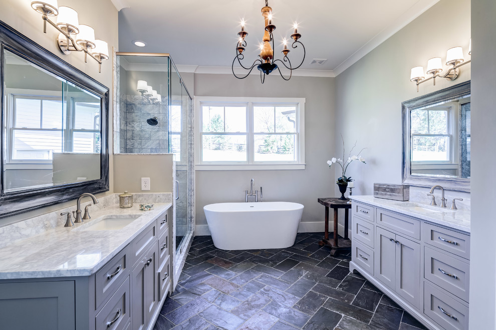 This is an example of a classic ensuite bathroom in Atlanta with shaker cabinets, grey cabinets, a freestanding bath, a corner shower, grey walls and a submerged sink.