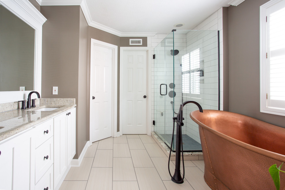 Стильный дизайн: главная ванная комната среднего размера в классическом стиле с фасадами в стиле шейкер, белыми фасадами, отдельно стоящей ванной, угловым душем, раздельным унитазом, белой плиткой, керамической плиткой, коричневыми стенами, полом из керамической плитки, врезной раковиной, столешницей из гранита, бежевым полом, душем с распашными дверями, бежевой столешницей, тумбой под две раковины и встроенной тумбой - последний тренд