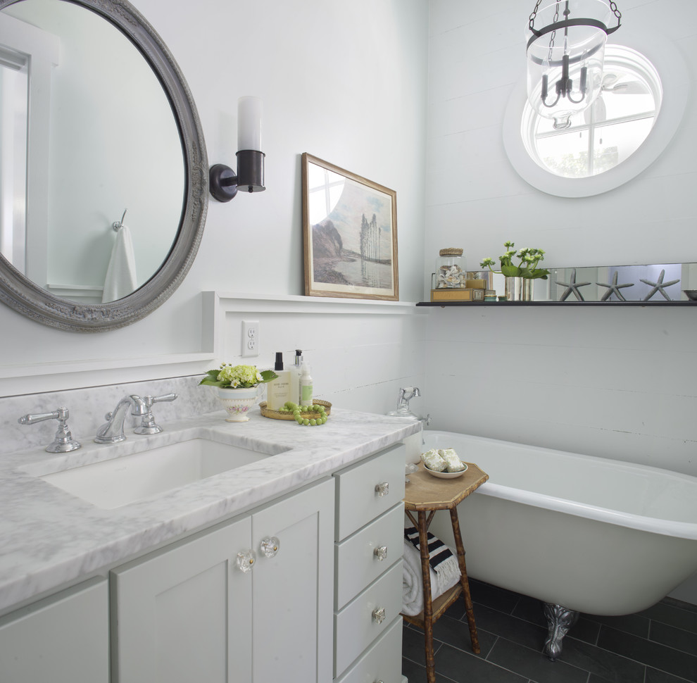 This is an example of a medium sized coastal ensuite bathroom in Atlanta with a claw-foot bath, marble worktops, shaker cabinets, white cabinets, white walls, porcelain flooring, a submerged sink, black floors and white worktops.