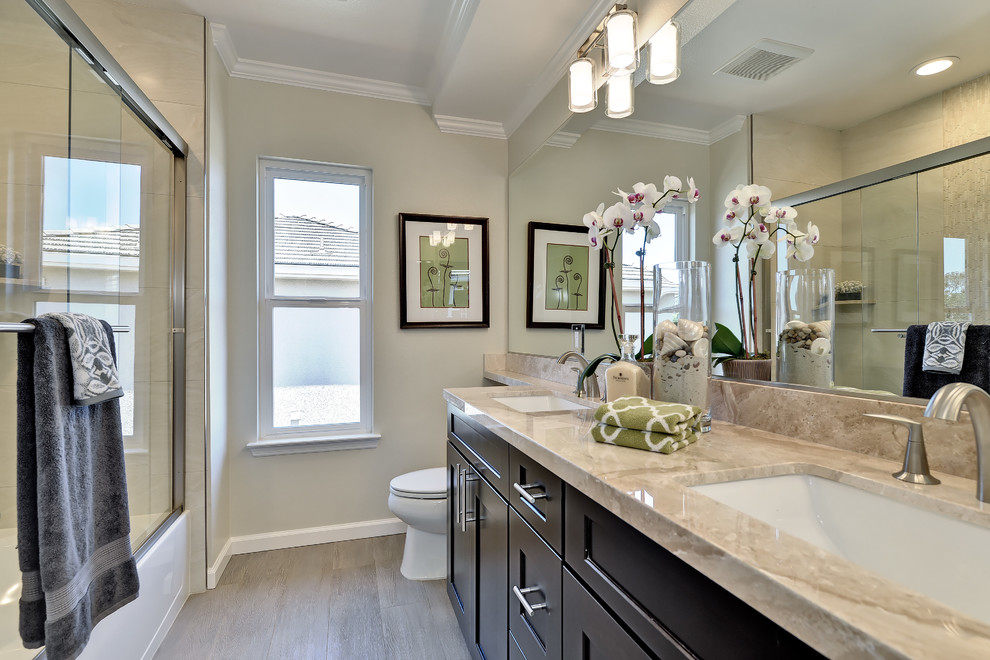 Esempio di una stanza da bagno tradizionale con pareti beige, pavimento in compensato, lavabo integrato e top in marmo