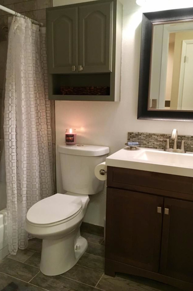 Example of a mid-sized transitional kids' laminate floor and brown floor bathroom design in Denver with flat-panel cabinets, dark wood cabinets, a two-piece toilet, white walls, an integrated sink and solid surface countertops