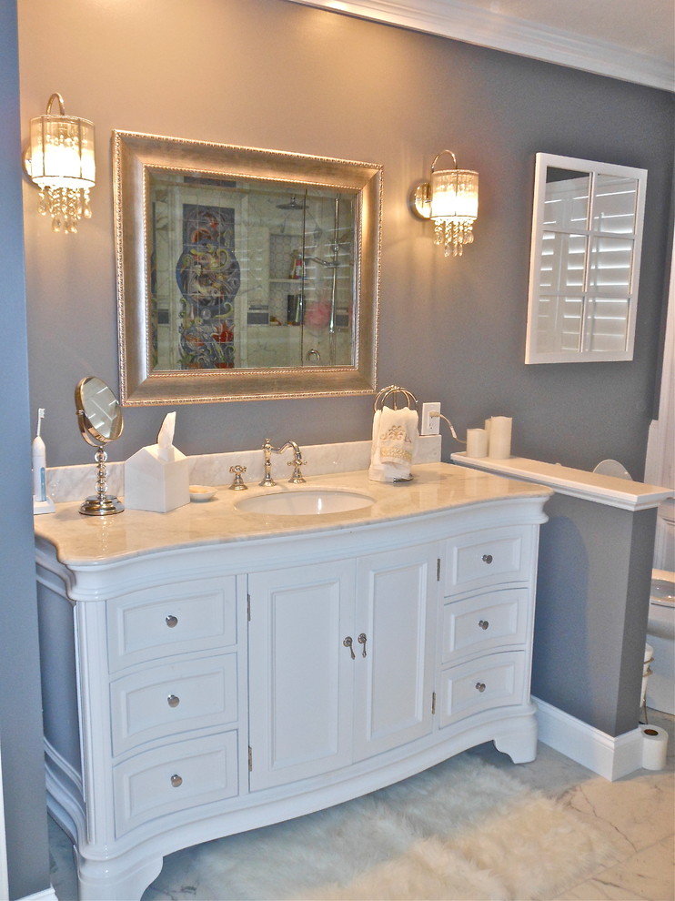 Medium sized traditional ensuite bathroom in Kansas City with freestanding cabinets, white cabinets, a built-in bath, a corner shower, a two-piece toilet, white tiles, porcelain tiles, grey walls, porcelain flooring, a console sink and marble worktops.