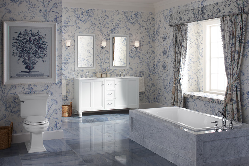 Foto på ett mellanstort vintage en-suite badrum, med luckor med infälld panel, vita skåp, ett platsbyggt badkar, en toalettstol med separat cisternkåpa, blå väggar, marmorgolv, ett undermonterad handfat, bänkskiva i akrylsten och blått golv