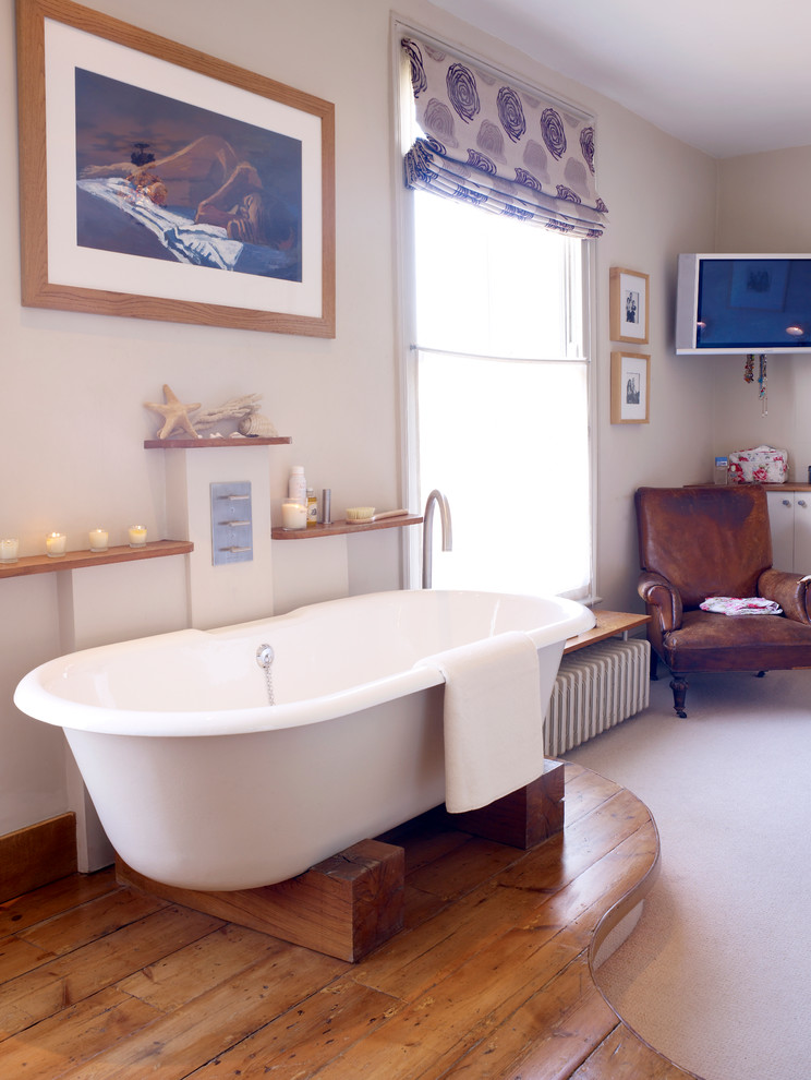 Ejemplo de cuarto de baño principal contemporáneo de tamaño medio con bañera exenta, paredes beige y suelo de madera en tonos medios