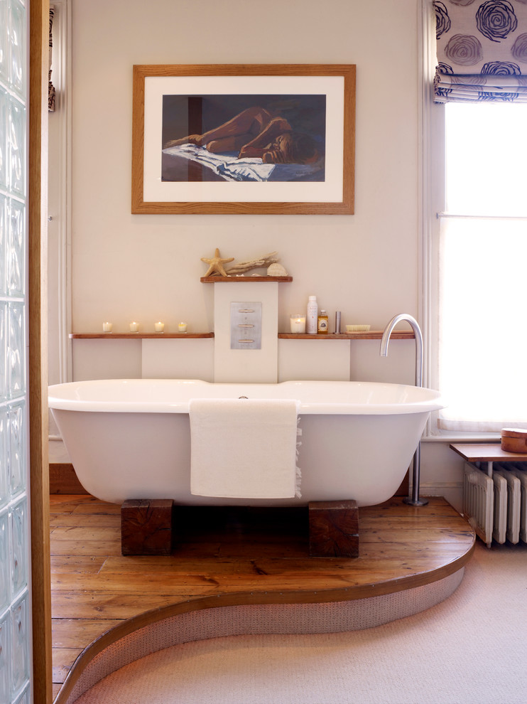 Example of a mid-sized trendy master medium tone wood floor freestanding bathtub design in London with beige walls