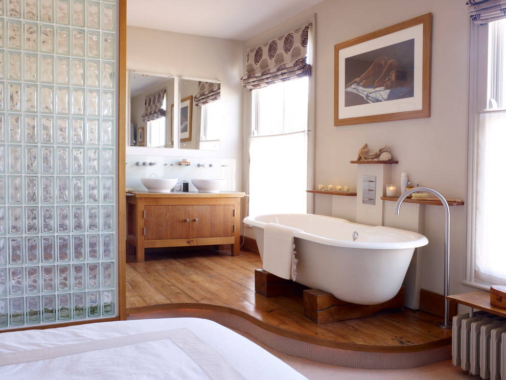 На фото: главная ванная комната среднего размера в современном стиле с настольной раковиной, плоскими фасадами, фасадами цвета дерева среднего тона, отдельно стоящей ванной, бежевыми стенами и паркетным полом среднего тона с