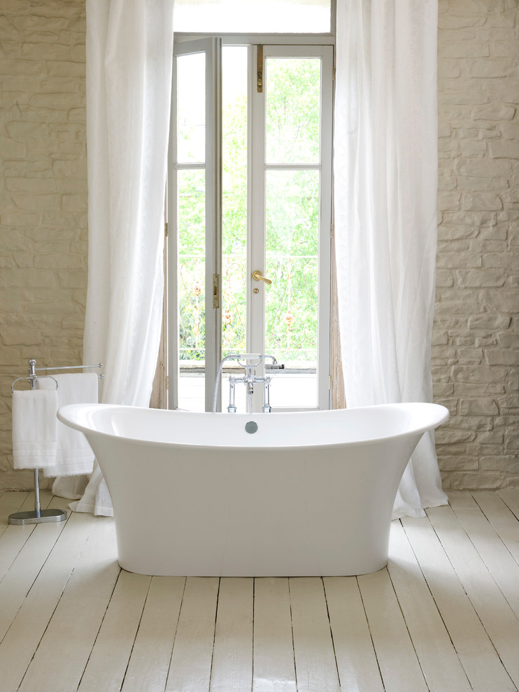 Klassisk inredning av ett mellanstort en-suite badrum, med ett fristående badkar, en dusch/badkar-kombination, beige kakel, stenkakel, beige väggar, målat trägolv, beiget golv och med dusch som är öppen