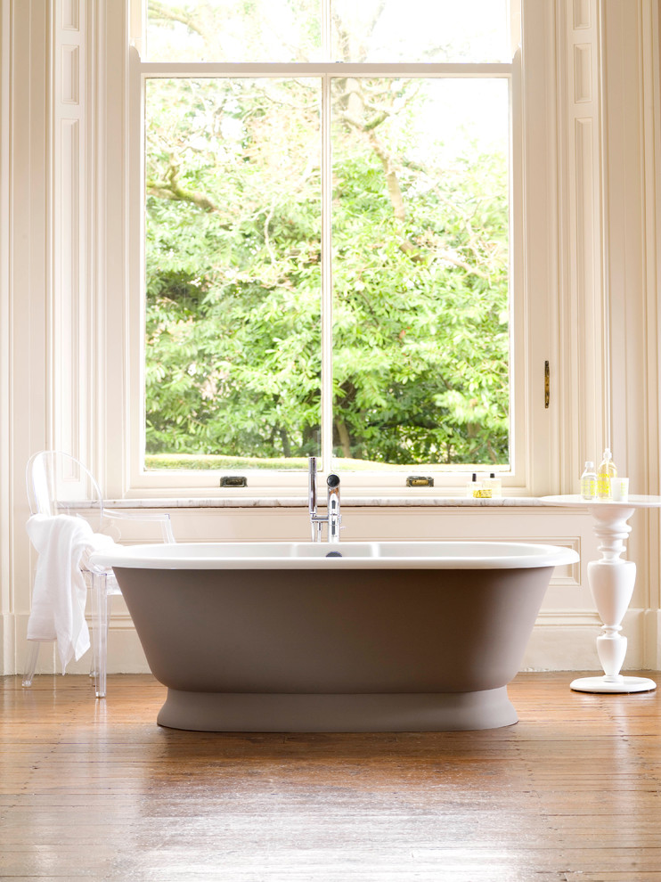 Ejemplo de cuarto de baño clásico con bañera exenta y suelo de madera en tonos medios