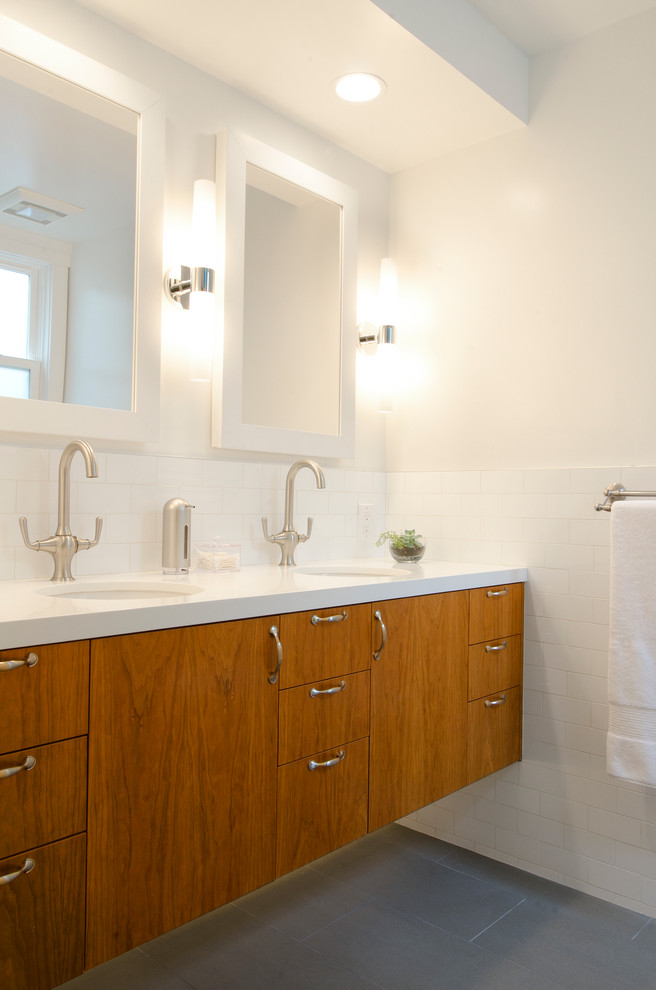 サンフランシスコにあるコンテンポラリースタイルのおしゃれな浴室 (アンダーカウンター洗面器、フラットパネル扉のキャビネット、中間色木目調キャビネット、白いタイル、サブウェイタイル、白い壁) の写真