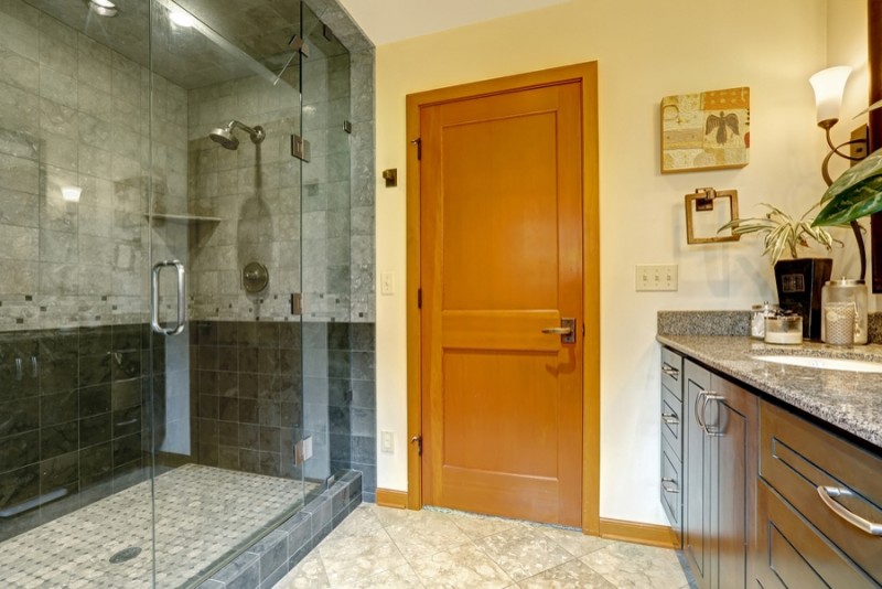 Inspiration för ett mellanstort funkis badrum med dusch, med luckor med upphöjd panel, skåp i mörkt trä, en dusch i en alkov, grå kakel, stenkakel, beige väggar, klinkergolv i keramik, ett undermonterad handfat, granitbänkskiva, beiget golv och dusch med gångjärnsdörr
