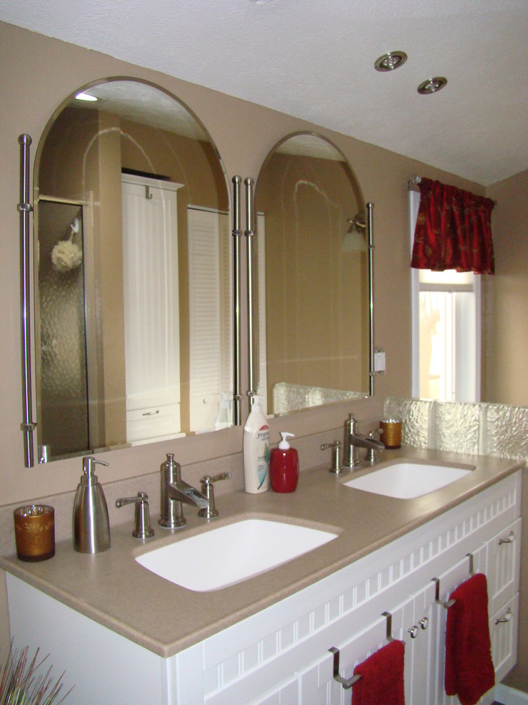 Immagine di una stanza da bagno con doccia classica di medie dimensioni con ante a filo, ante bianche, pareti beige, lavabo sottopiano, top in laminato, doccia alcova e porta doccia scorrevole