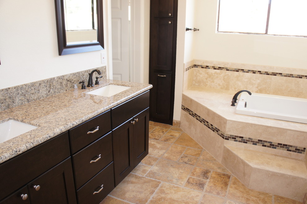 Trendy beige tile and porcelain tile drop-in bathtub photo in San Diego with shaker cabinets, dark wood cabinets, quartzite countertops and a two-piece toilet