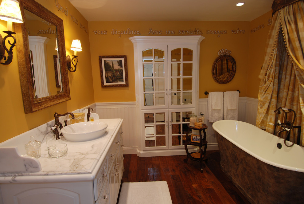 На фото: детская ванная комната среднего размера в классическом стиле с накладной раковиной, фасадами с выступающей филенкой, белыми фасадами, мраморной столешницей, отдельно стоящей ванной, желтыми стенами и паркетным полом среднего тона