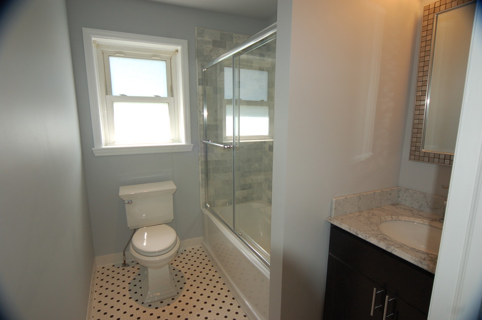 Elegant white tile and subway tile alcove bathtub photo in Philadelphia with an undermount sink, recessed-panel cabinets, black cabinets, marble countertops and a two-piece toilet