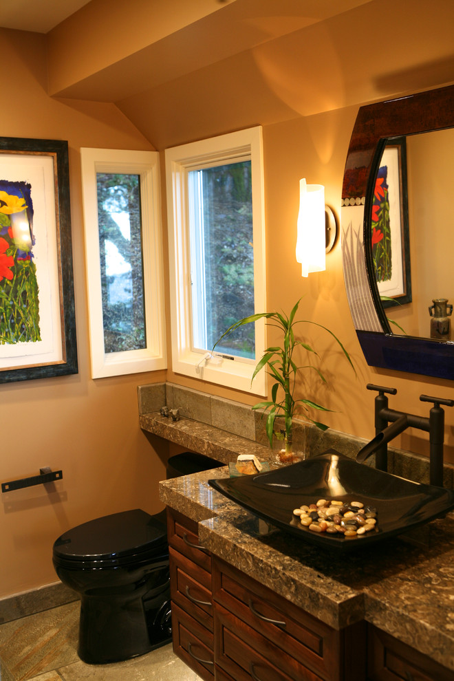 Cette image montre une salle de bain design avec une vasque, un placard avec porte à panneau surélevé, un plan de toilette en granite, WC à poser, un carrelage marron et des carreaux de porcelaine.