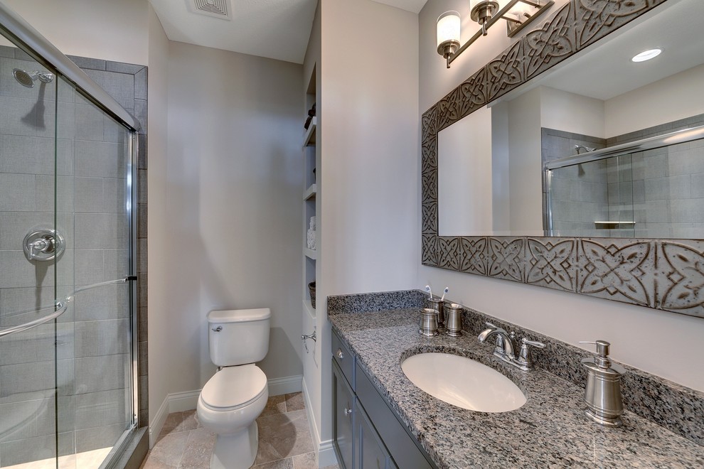 Bild på ett stort vintage badrum med dusch, med ett undermonterad handfat, luckor med infälld panel, grå skåp, granitbänkskiva, en dusch i en alkov, en toalettstol med separat cisternkåpa, grå kakel, keramikplattor, grå väggar och klinkergolv i keramik