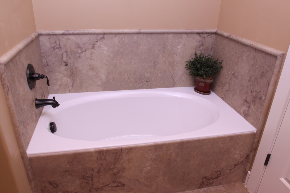 Idee per una stanza da bagno padronale classica di medie dimensioni con vasca da incasso, piastrelle beige, pareti arancioni, top in superficie solida e lastra di pietra