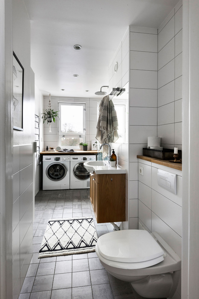 Exempel på ett modernt badrum med dusch, med luckor med infälld panel, skåp i mellenmörkt trä, våtrum, en vägghängd toalettstol, vit kakel, vita väggar, ett integrerad handfat, grått golv och med dusch som är öppen