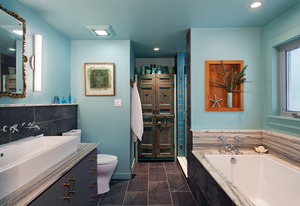 Exemple d'une salle de bain principale méditerranéenne de taille moyenne avec une grande vasque, un plan de toilette en granite, un carrelage gris, des carreaux de porcelaine, un mur bleu, un sol en carrelage de céramique, un placard à porte plane, des portes de placard grises et une baignoire encastrée.