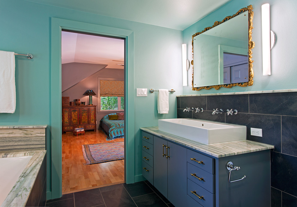 Inspiration för mellanstora medelhavsstil en-suite badrum, med ett avlångt handfat, släta luckor, blå skåp, granitbänkskiva, svart kakel, porslinskakel, blå väggar och klinkergolv i keramik