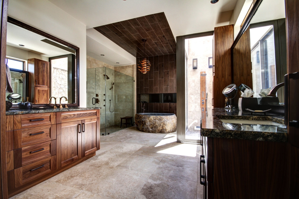 На фото: большая главная ванная комната в современном стиле с фасадами в стиле шейкер, темными деревянными фасадами, отдельно стоящей ванной, угловым душем, унитазом-моноблоком, коричневой плиткой, керамической плиткой, белыми стенами, полом из известняка, врезной раковиной, столешницей из гранита, бежевым полом и душем с распашными дверями