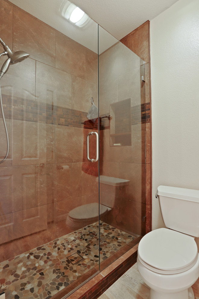 Photo of a classic bathroom in Sacramento with medium wood cabinets, a corner shower, a wall mounted toilet, beige tiles, beige walls, porcelain flooring, a submerged sink, granite worktops, brown floors, a hinged door and beige worktops.