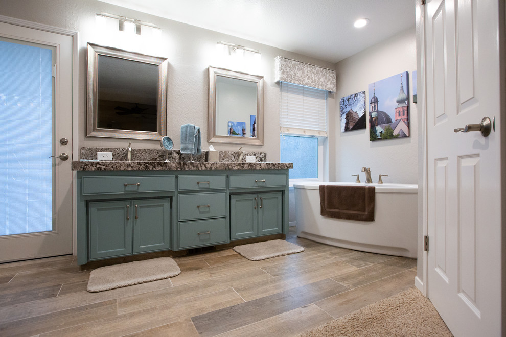 Modern inredning av ett stort en-suite badrum, med blå skåp, ett fristående badkar, en hörndusch, en toalettstol med hel cisternkåpa, vita väggar, ett undermonterad handfat, granitbänkskiva, brunt golv och dusch med gångjärnsdörr