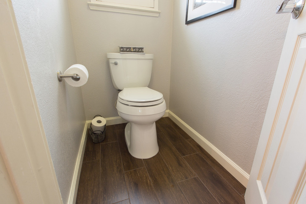 Inredning av ett modernt toalett, med skåp i mörkt trä, porslinskakel, grå väggar, klinkergolv i porslin, ett undermonterad handfat och bänkskiva i kvarts