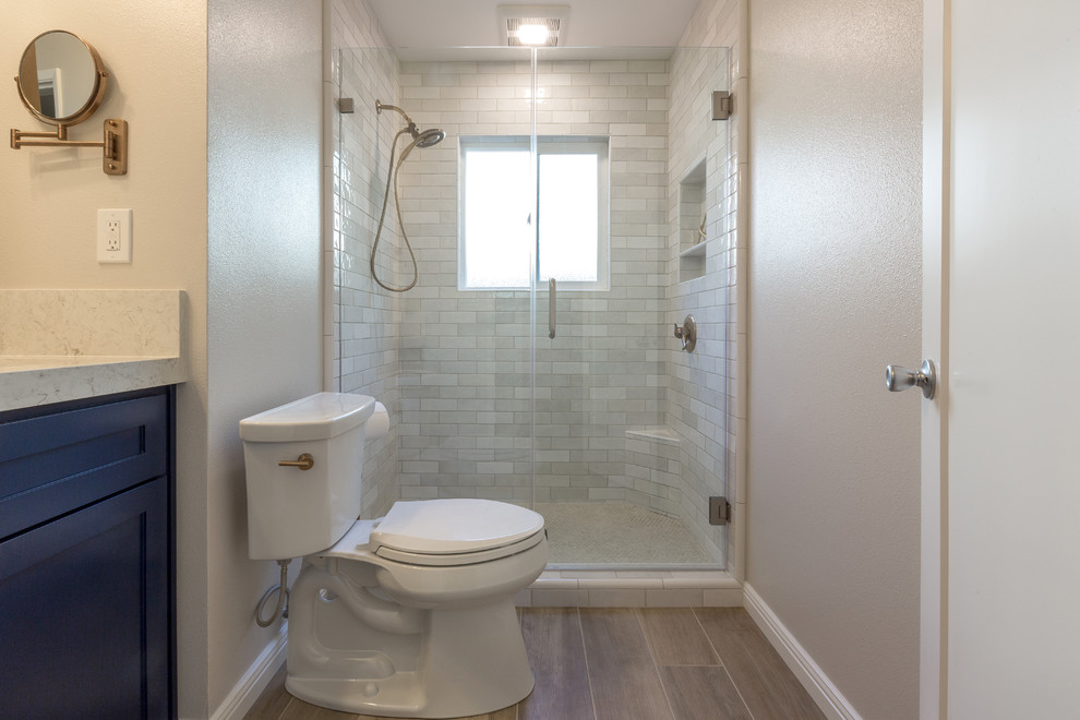 Esempio di una stanza da bagno per bambini moderna con ante blu, doccia ad angolo, WC monopezzo, piastrelle bianche, pareti bianche, lavabo sottopiano, top in quarzite, pavimento marrone, porta doccia a battente e top bianco