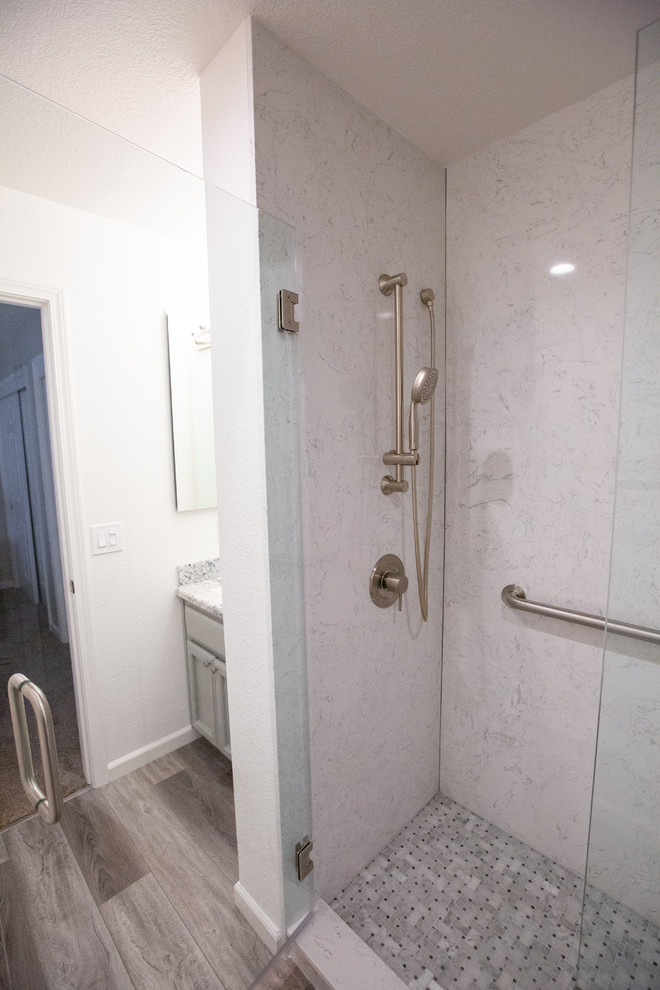 Bild på ett litet funkis badrum för barn, med grå skåp, en hörndusch, vita väggar, ett undermonterad handfat, granitbänkskiva, brunt golv och dusch med gångjärnsdörr