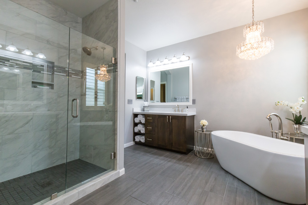Modernes Badezimmer mit dunklen Holzschränken, freistehender Badewanne, Eckdusche, grauen Fliesen, Porzellan-Bodenfliesen, Unterbauwaschbecken und Quarzwerkstein-Waschtisch in Sacramento